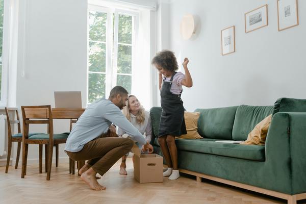 A mother, father, and daughter happily unpacking a box.